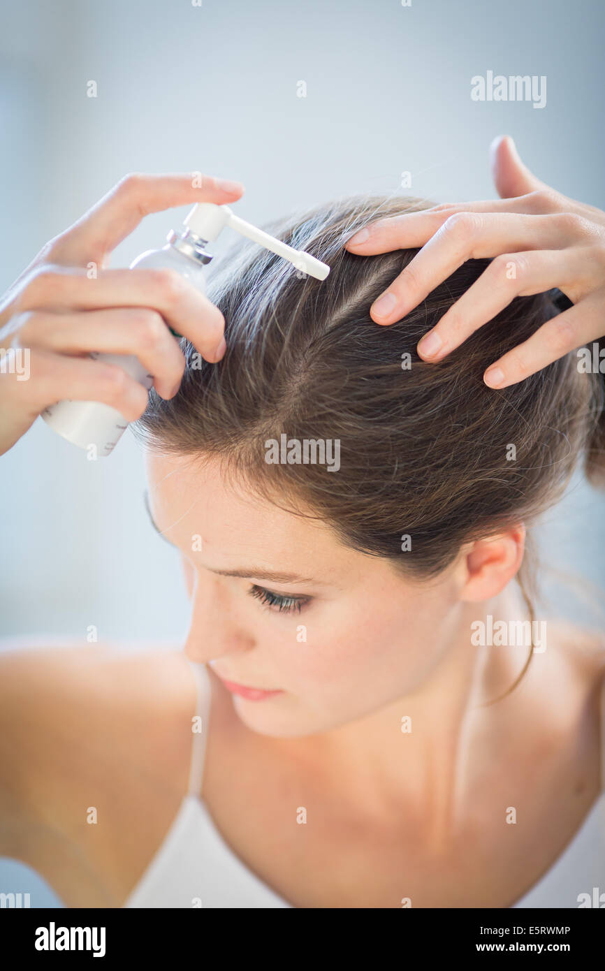 Woman applying hair lotion Stock Photo - Alamy