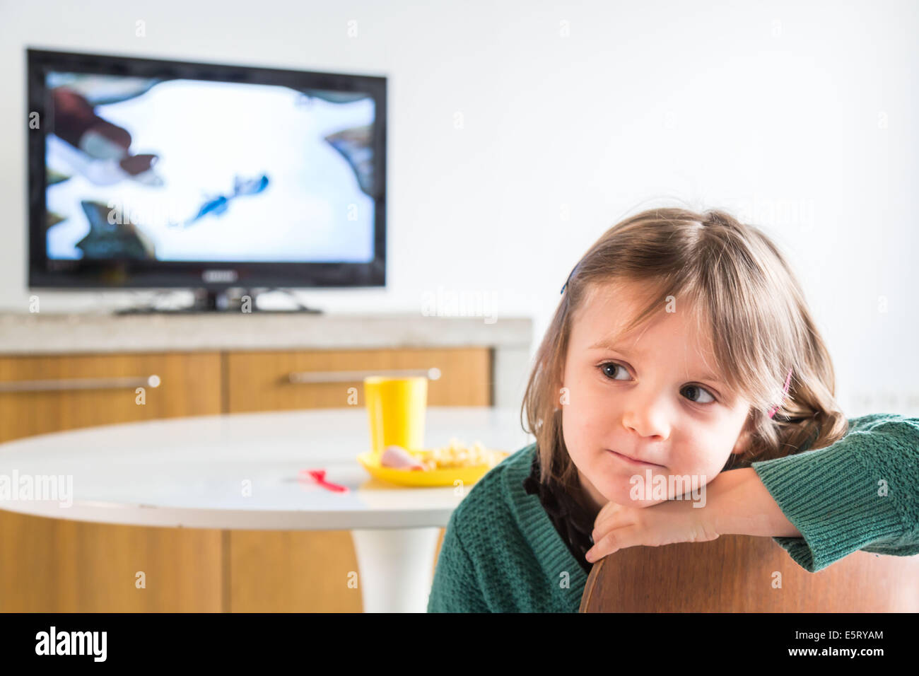 Girl watching TV while eating lunch Stock Photo Alamy