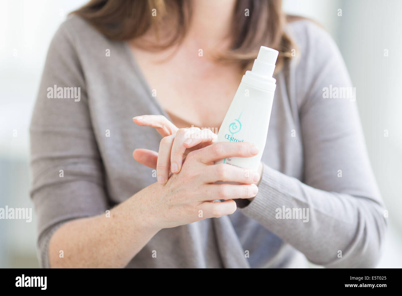 Woman applying an estrogen gel on her hands for a Hormone Replacement Therapy, in order to releive the undesirable effects of Stock Photo