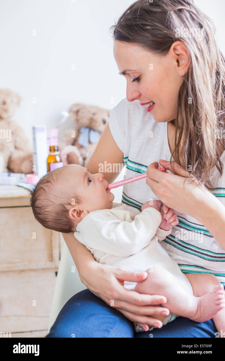 Mother giving her 3 months old baby boy Doliprane ® with a pipette. Stock Photo