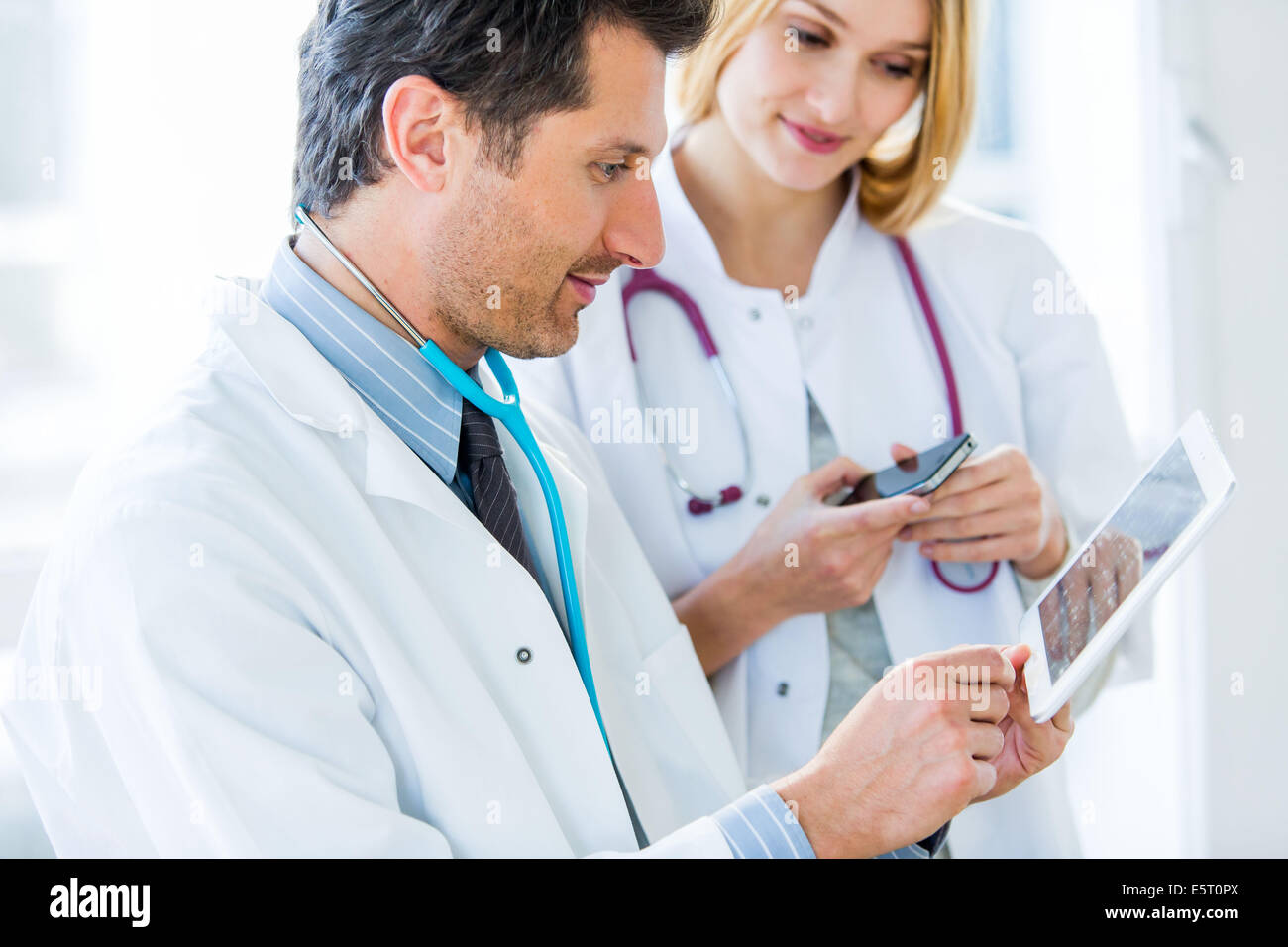 Doctors using a tablet PC and Iphone®. Stock Photo