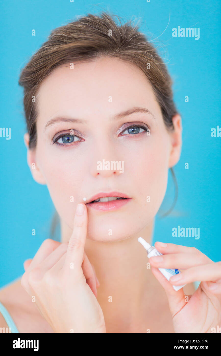 Woman applying cream on her lips as a treatment for a cold sore Stock