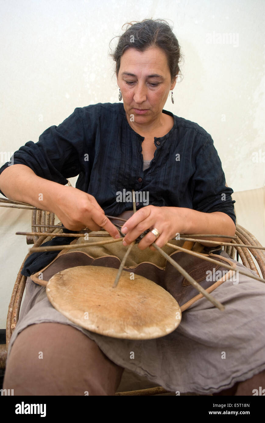 Woman weaving the base of a willow basket at a country games and craft fair, Selborne, Hampshire, UK. Stock Photo