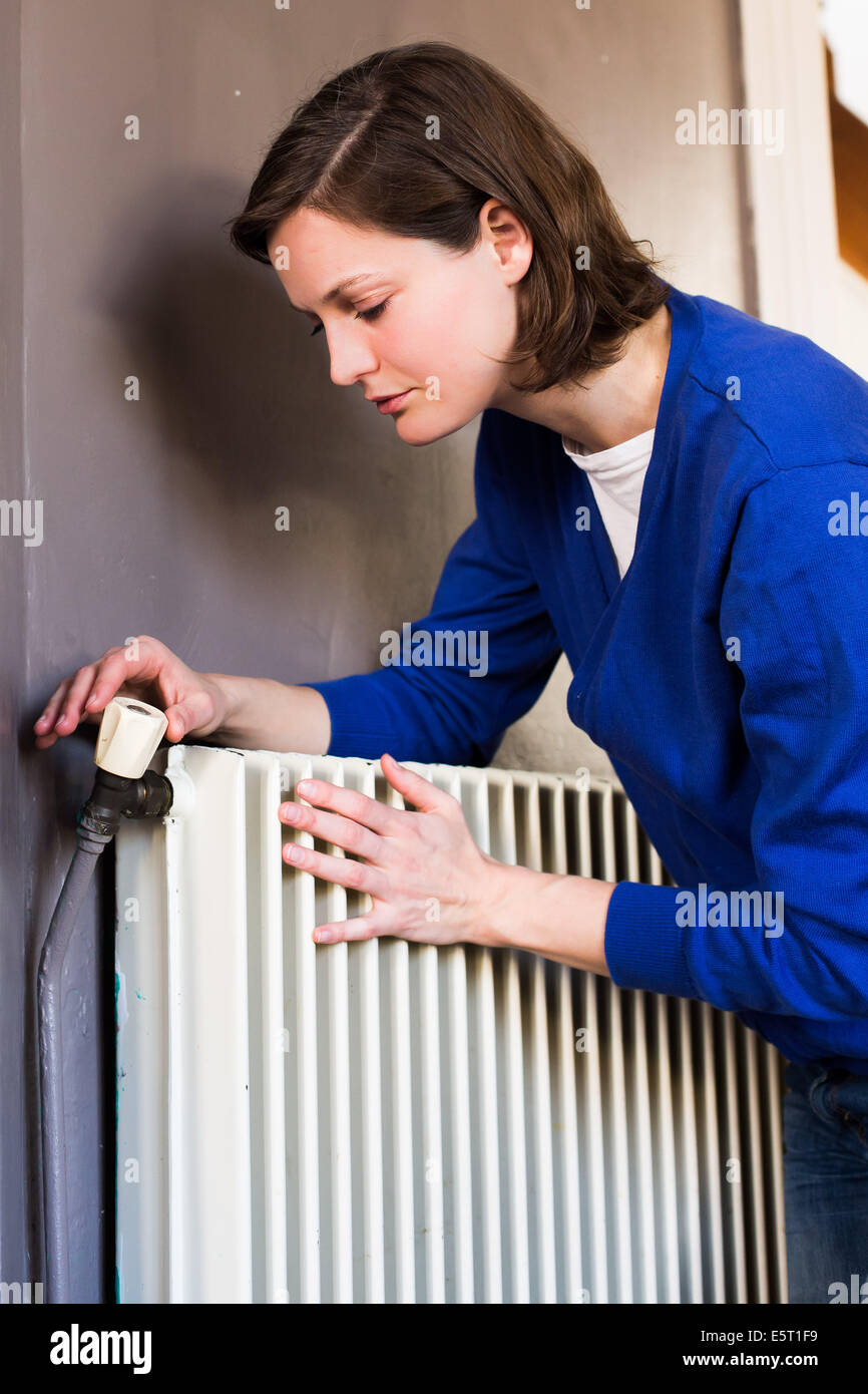 Woman adjusting a thermostatic radiator valve on a domestic radiator. Stock Photo
