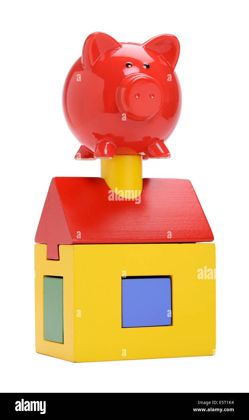 A toy wooden house with a red piggy bank on top Stock Photo