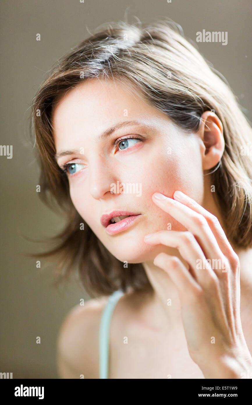 Woman checking her face in the mirror Stock Photo - Alamy