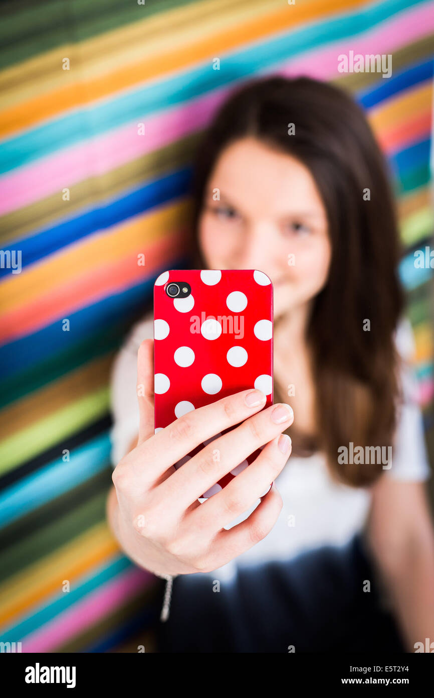 Teenage girl taking picture with camera phone. Stock Photo