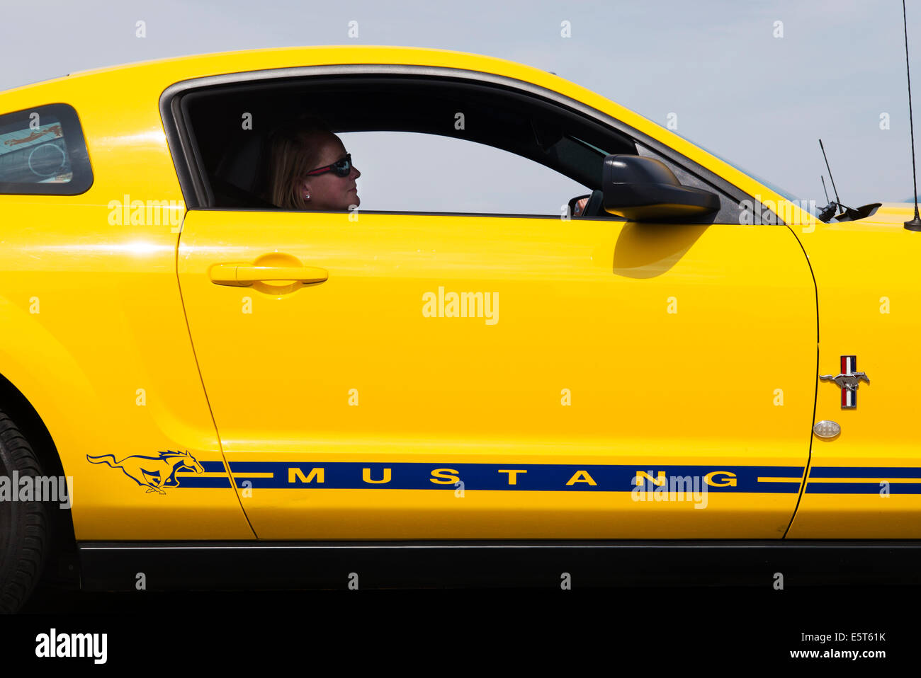Woman driving a Yellow Ford Mustang. Classic American car Stock Photo
