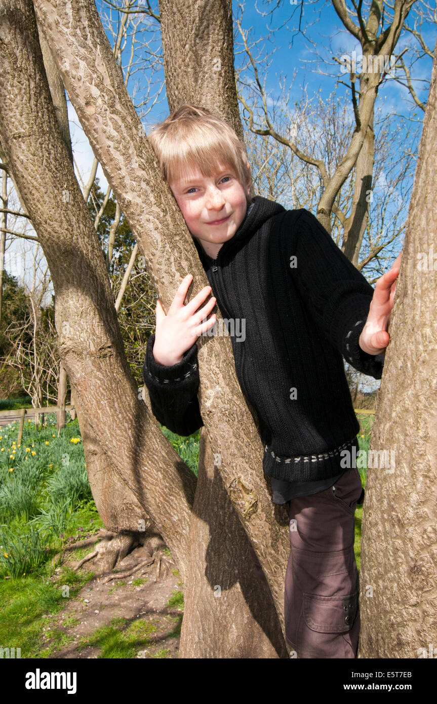 Smilling boy leaning on tree Stock Photo - Alamy