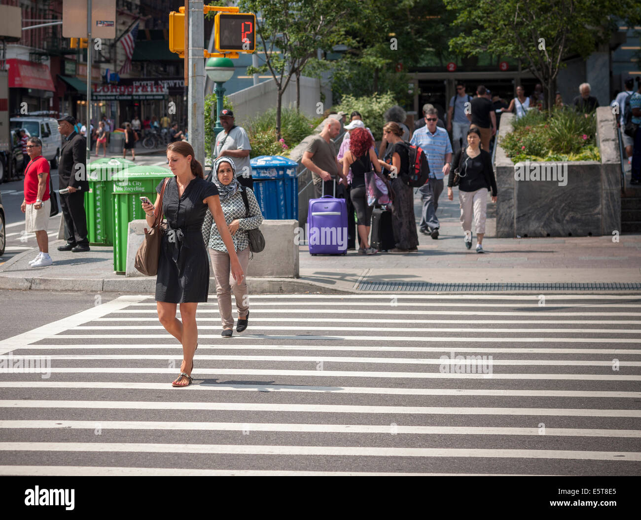A pedestrian using her smartphone crosses West 96th Street at Broadway in New York Stock Photo