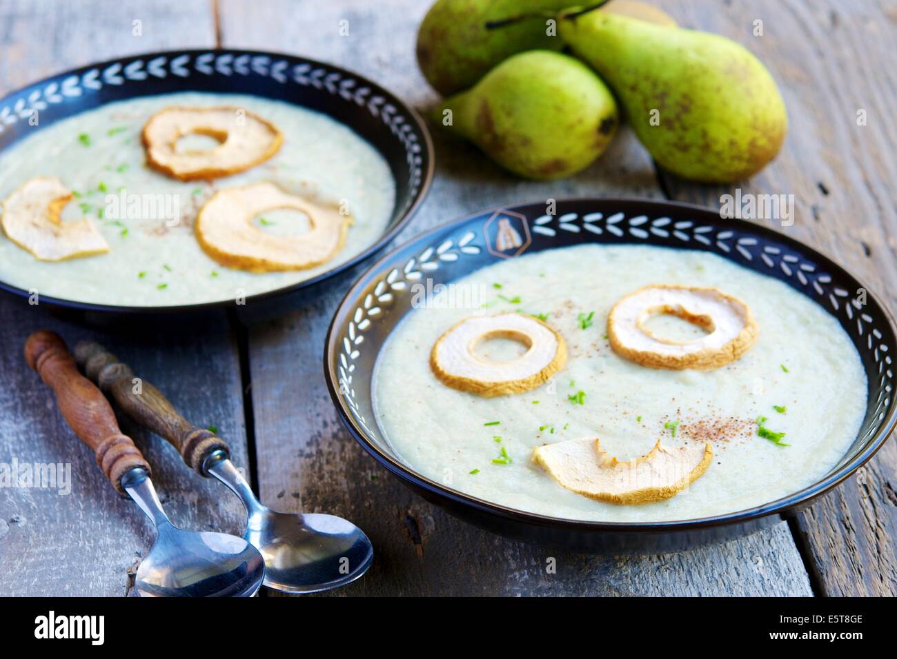 A creamy fall season soup with pears and celery root, garnished with dried apple rings. Stock Photo