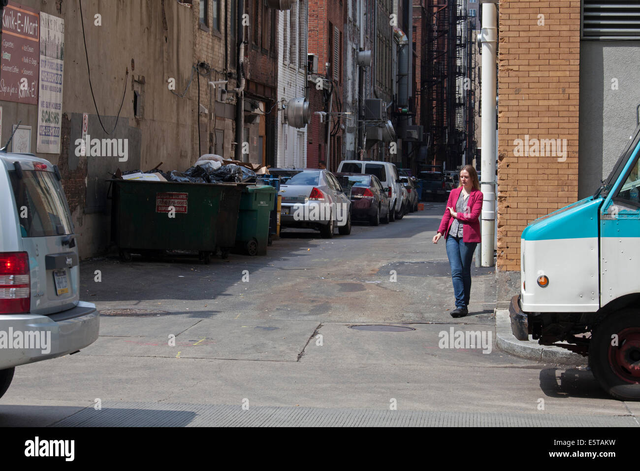 Pittsburgh, Pennsylvania - A woman stands in an alley, smoking a cigarette. Stock Photo