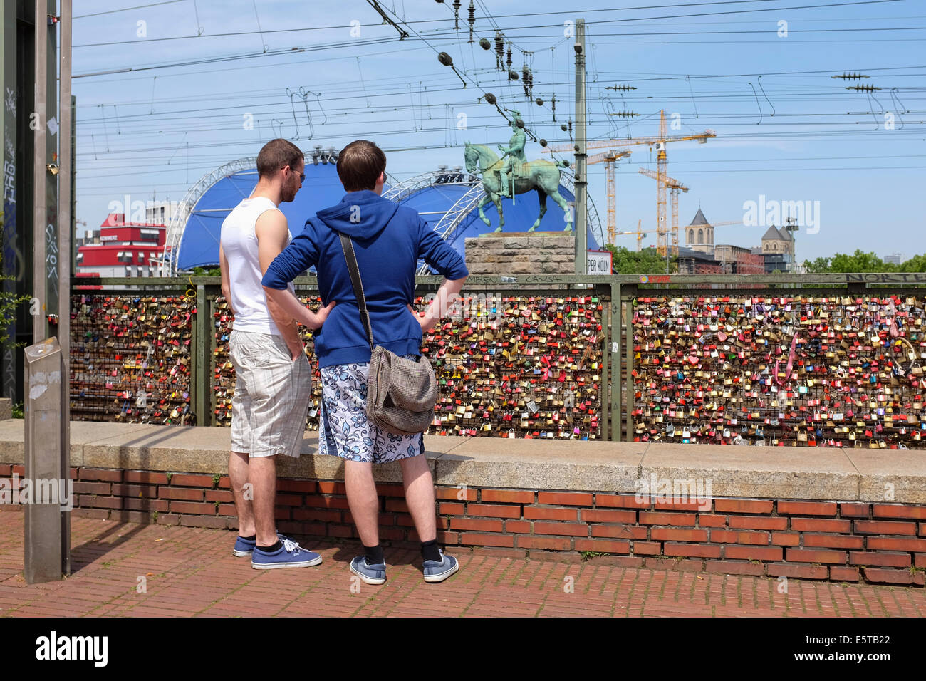 Two men looking at padlocks on the wall of love in the Hohenzollern Bridge in Cologne, Germany Stock Photo