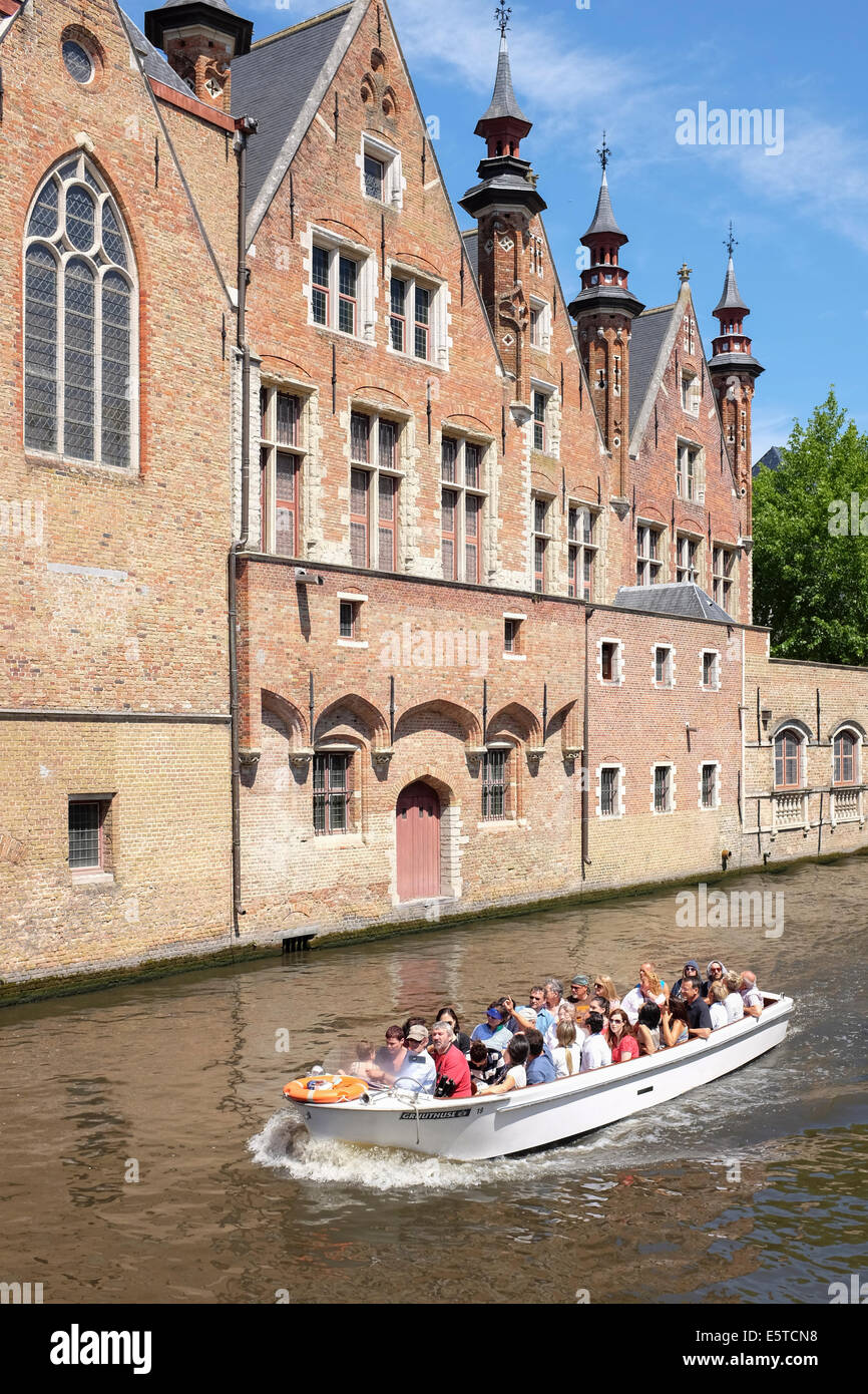 Flock of tourists on a boat ride in the canals of Bruges, Belgium Stock Photo
