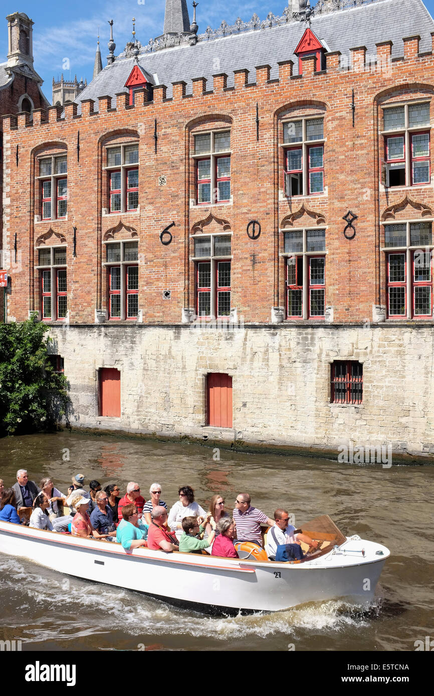 Flock of tourists on a boat ride in the canals of Bruges, Belgium Stock Photo