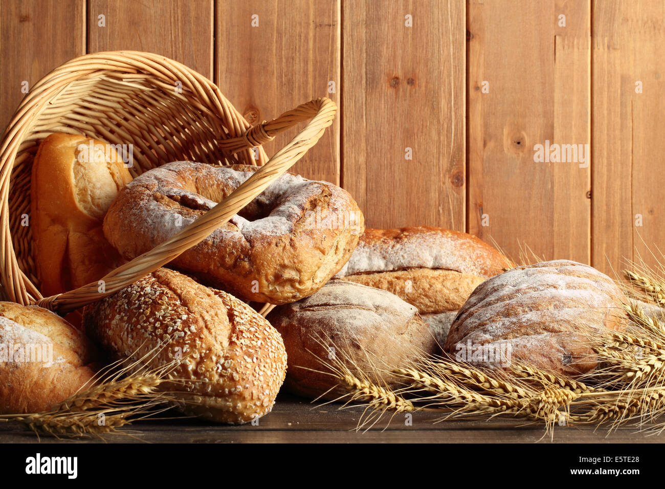 Whole grain wheat bread in basket with wheat ears. Stock Photo