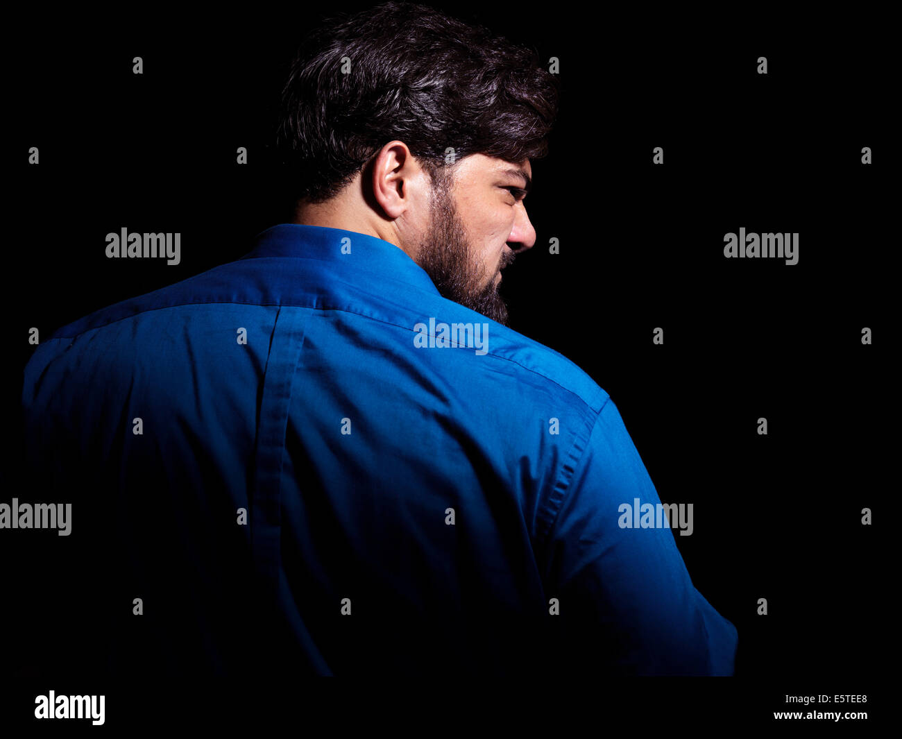 Portrait of an angry middle aged man looking over his shoulder isolated on black background Stock Photo