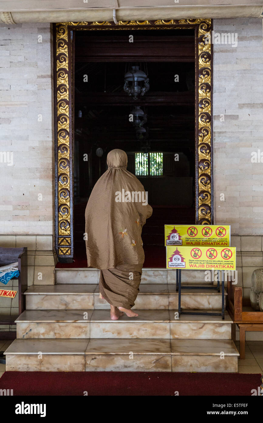 Yogyakarta, Java, Indonesia.  Woman Entering the Great Mosque, Masjid Gedhe Kauman, mid-18th. Century.  No Cell Phones Permitted Stock Photo