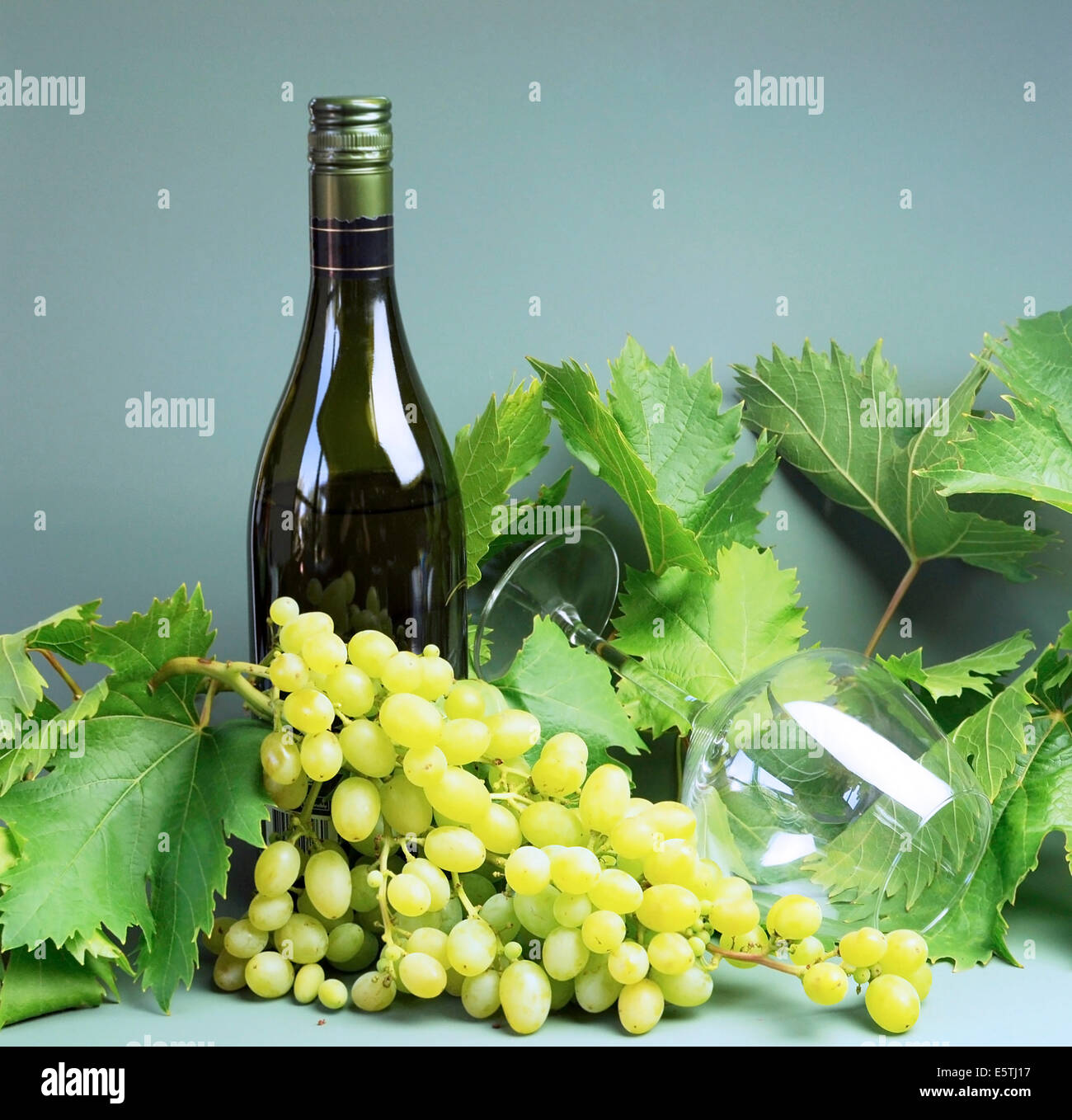 Bottle of white wine, wine glass with a large bunch of sultana grapes ...