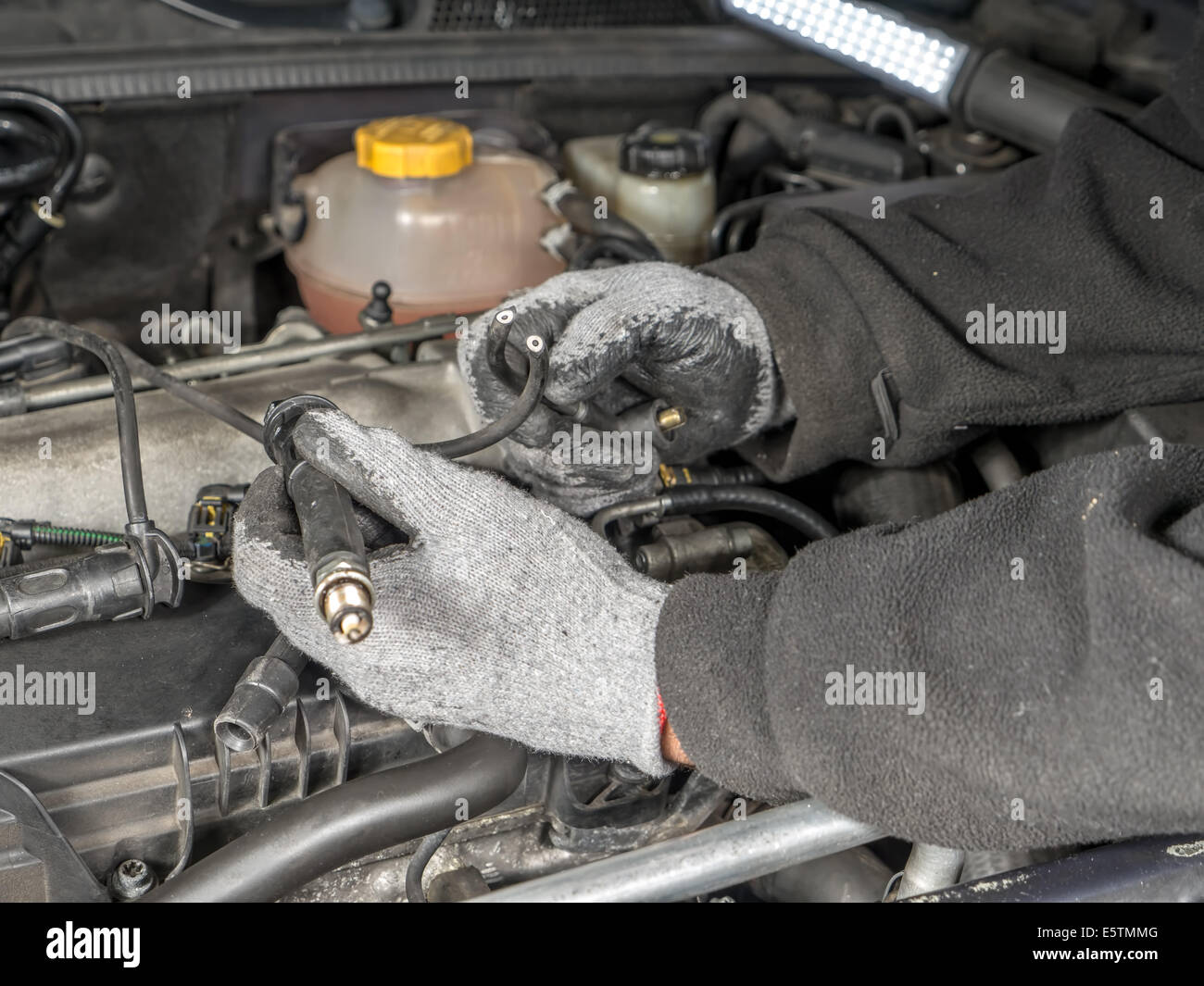 Auto mechanic replacing broken Diesel glow plug wire in car diesel engine compartment Stock Photo