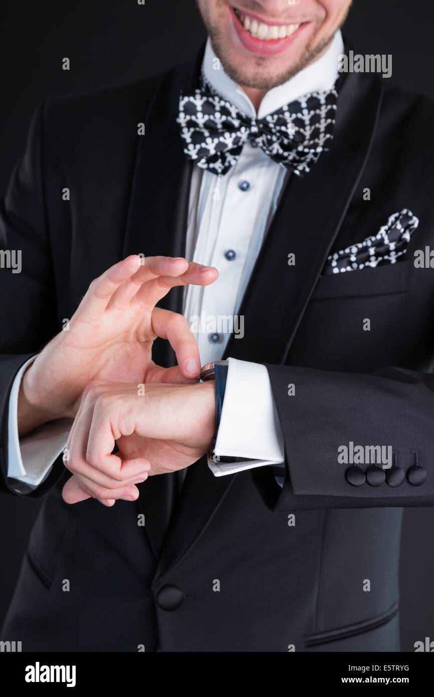 Man in a tuxedo winds up watches Stock Photo