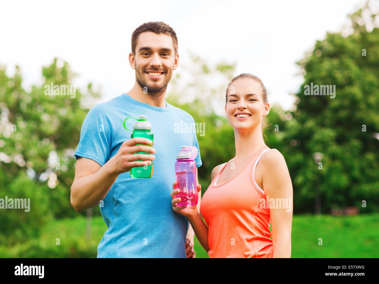 smiling couple with bottles of water outdoors Stock Photo