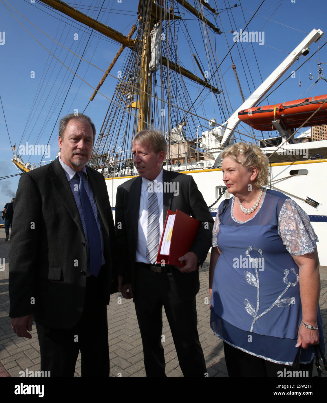 Rostock-Warnemuende, Germany. 06th Aug, 2014. Attorney Rainer Dietz (C) and the parents of Jenny Boeken, who was killed in an accident on board of the 'Gorch Fock', Marlis and Uwe Boeken, stand in front of the sailing school ship in Rostock-Warnemuende, Germany, 06 August 2014. Representatives of the administrative court Aachen are going to investigate on site if there was a particular danger of life during the service practice. The parents claimed for indemnification of 40,000 euros from the Federal Republic of Germany. Photo: Bernd Wuestneck/dpa/Alamy Live News Stock Photo