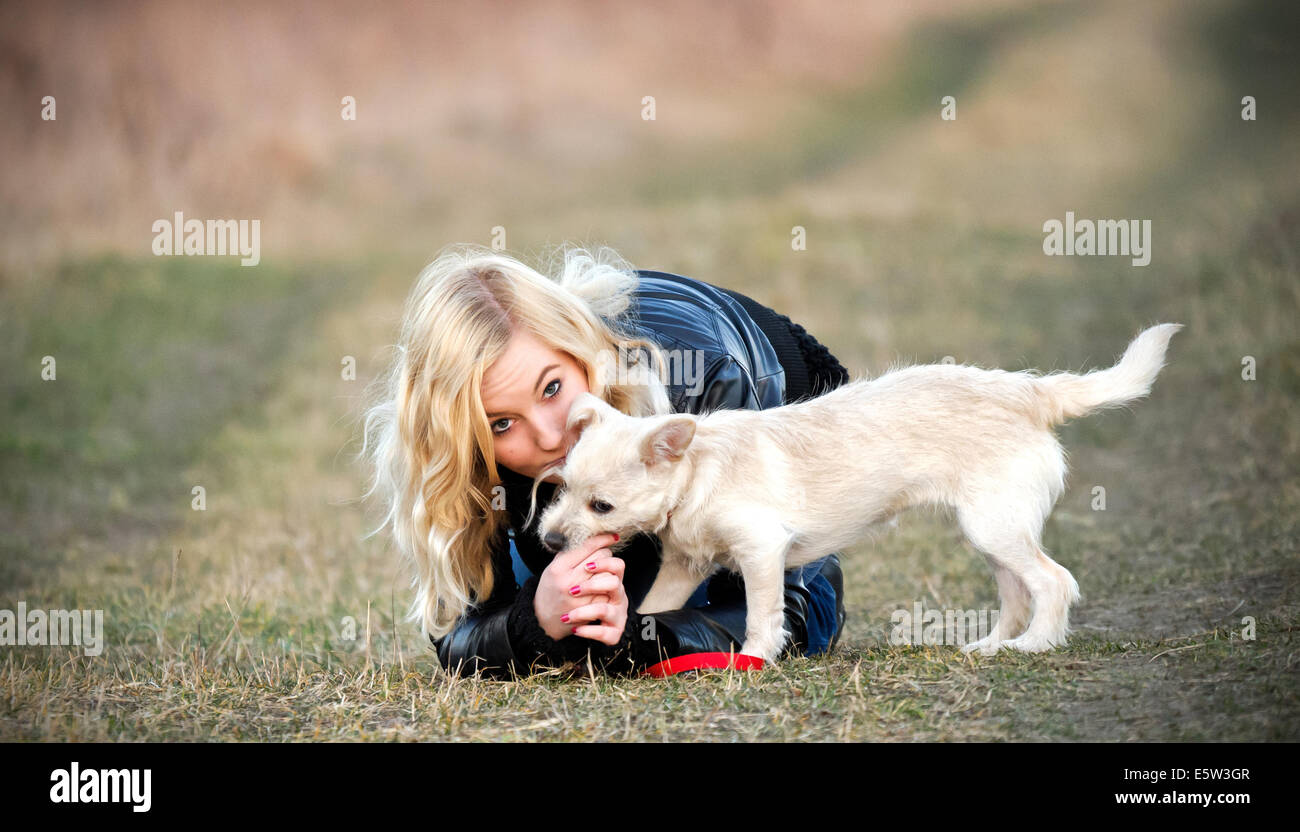 Blond girl playing with her puppy on the field Stock Photo - Alamy