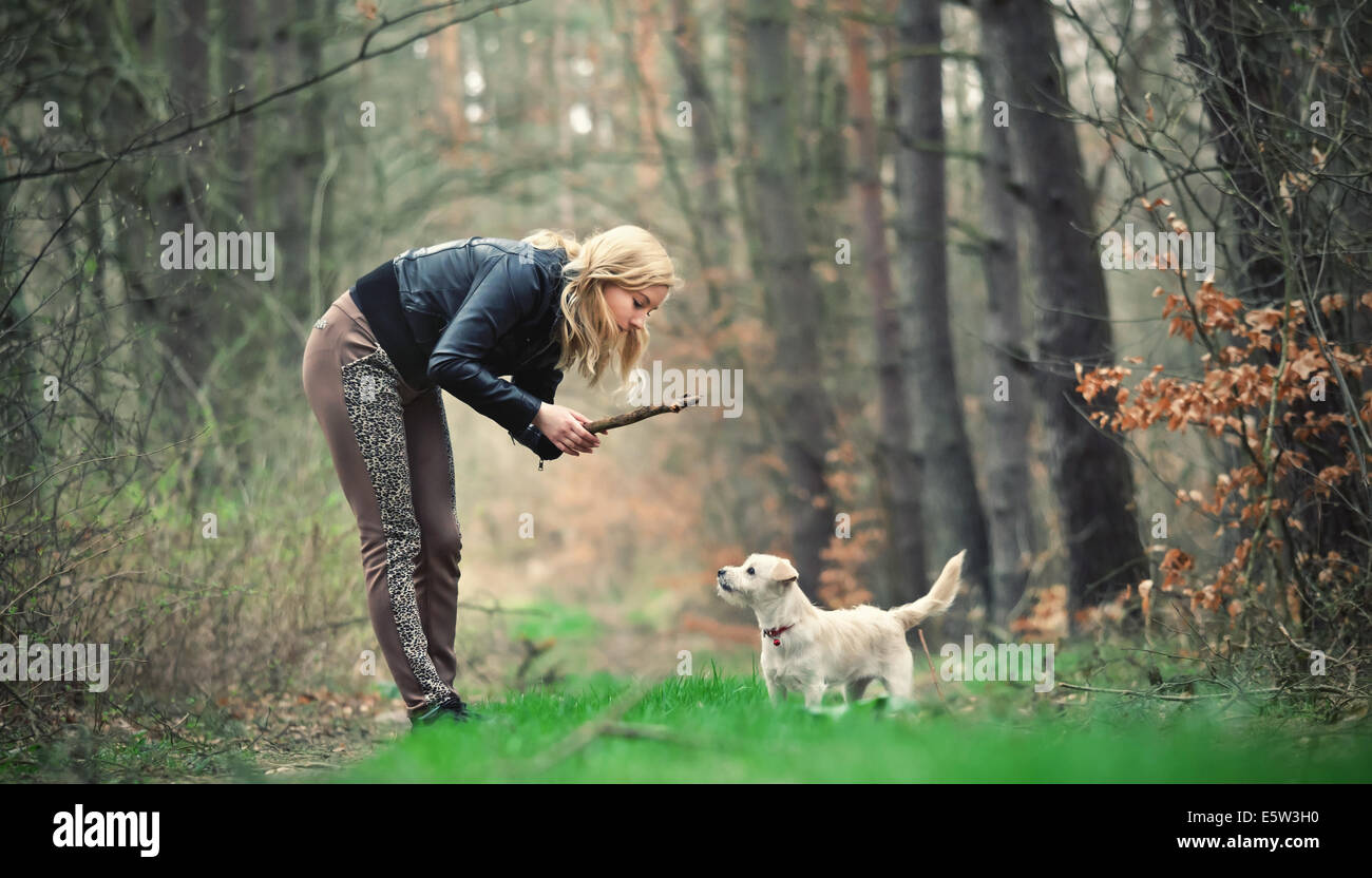 Blond girl playing with her puppy in the forest Stock Photo - Alamy