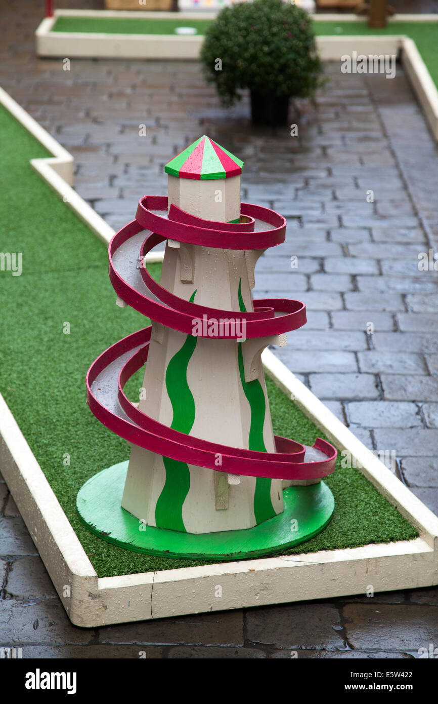 Old traditional wooden Helter-Skelter, a Childrens's fairground slide at Manchester, UK August 2014. Mini Crazy Golf, playing mini outdoor 9-hole asto turf crazy golf courses, minigolf, mini-putt, adventure midget golf, or putt-putt at Dig the City Deansgate, an annual urban gardening festival delivered by Manchester's Business Improvement District – BID.   Floral displays, bus stops and a Vimto garden transformed Manchester city centre as Dig the City returned.   Sixteen show gardens on display during the urban gardening festival, in August Stock Photo