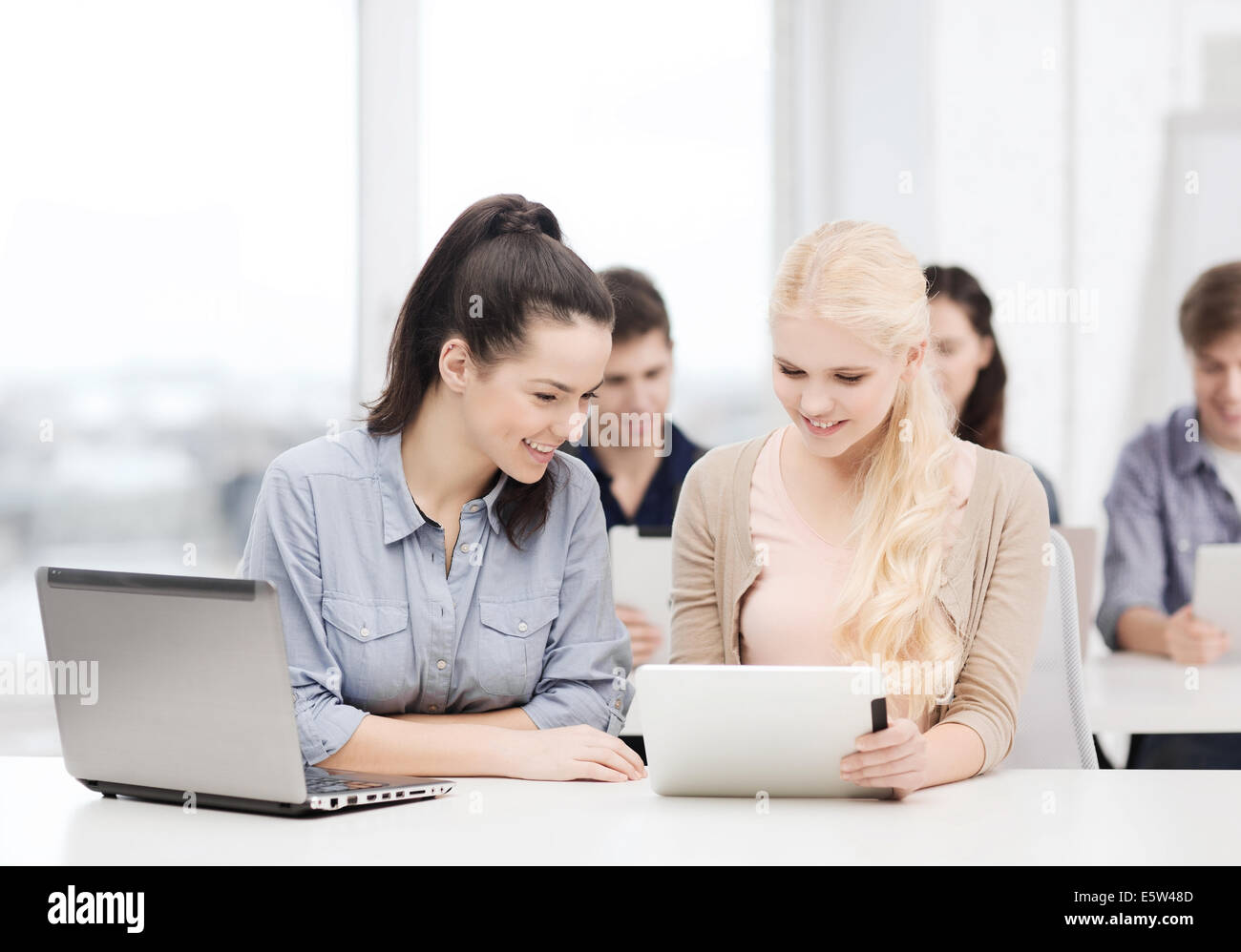 two smiling students with laptop and tablet pc Stock Photo - Alamy