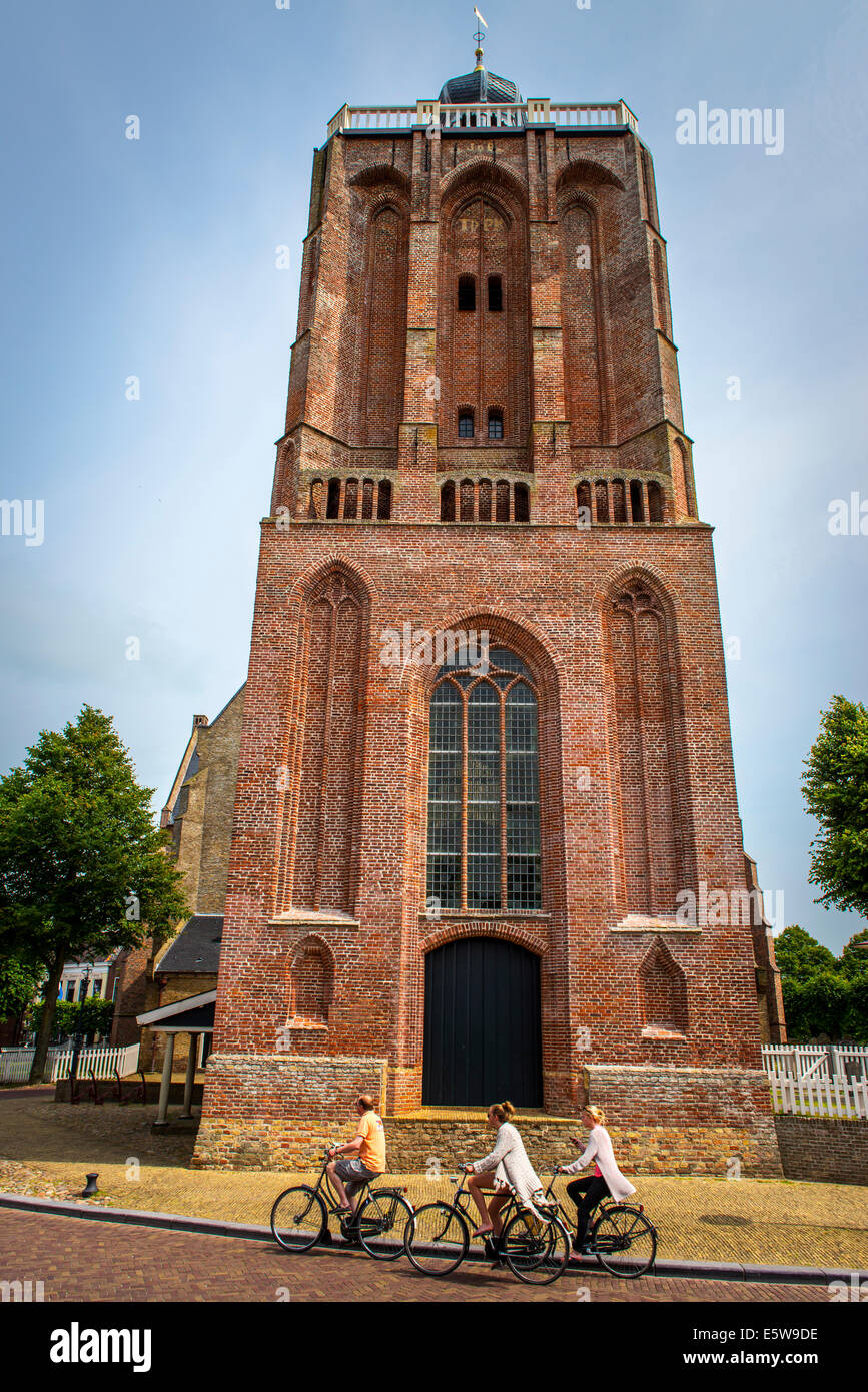 riding bicycles past a church in Workum, St. Gertrudis, Sint Gertrudiskerk, Friesland, holland, netherlands Stock Photo