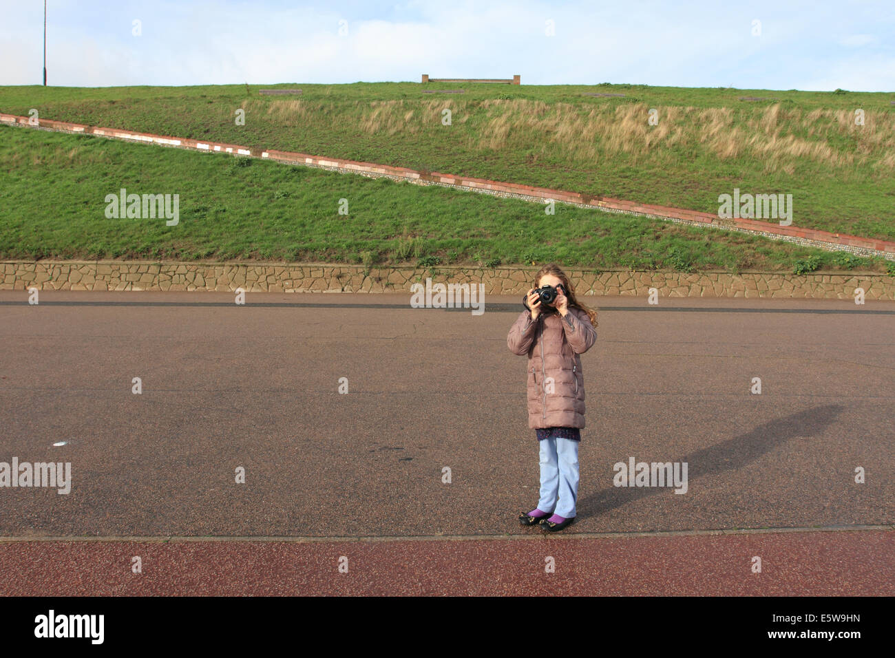 little girl standing and taking picture, winter coat.Norfolk, UK Stock Photo