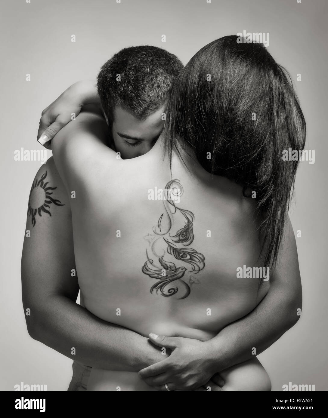 Black and white studio portrait of tattoos on a man and beautiful young nude hispanic woman Stock Photo pic