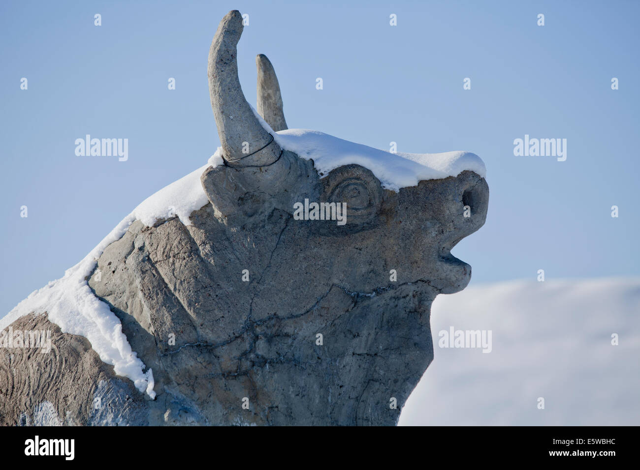 Stone statue of bull with horns covered in snow Stock Photo