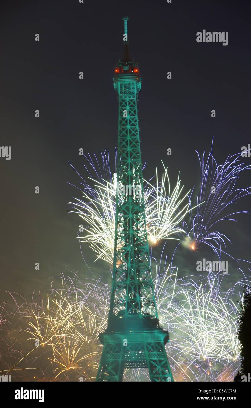 Fireworks shine on the night Eiffel Tower that has green lights on Bastille Day Stock Photo