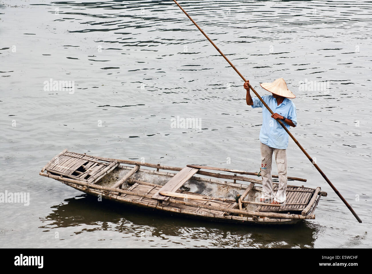 Oarsman punting down the river on a custom built bamboo raft in north Vietnam. Traditional mode of transport on rivers and lakes. Rural scene and life Stock Photo