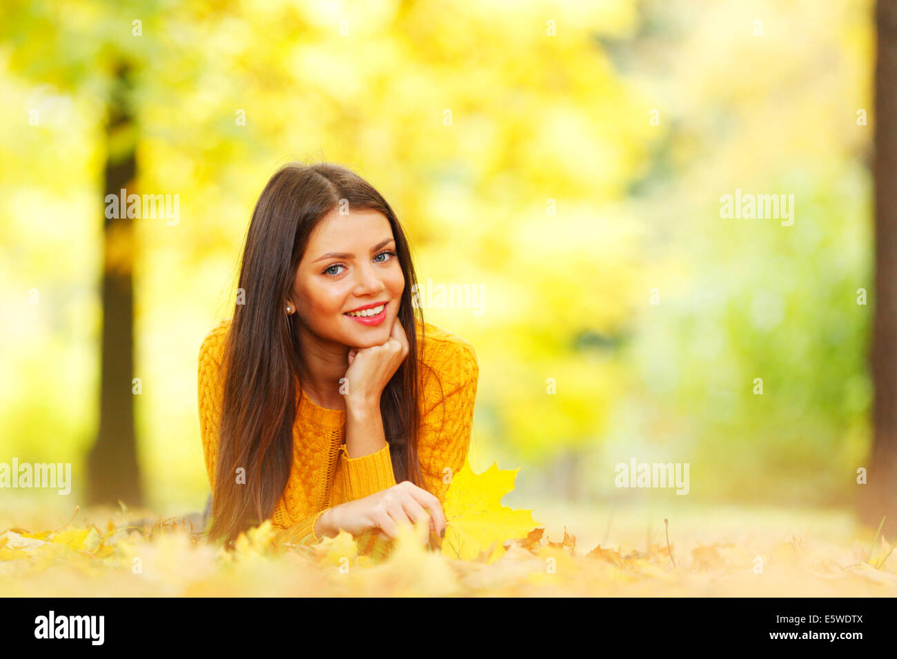 Girl laying on leafs in the autumn park Stock Photo - Alamy