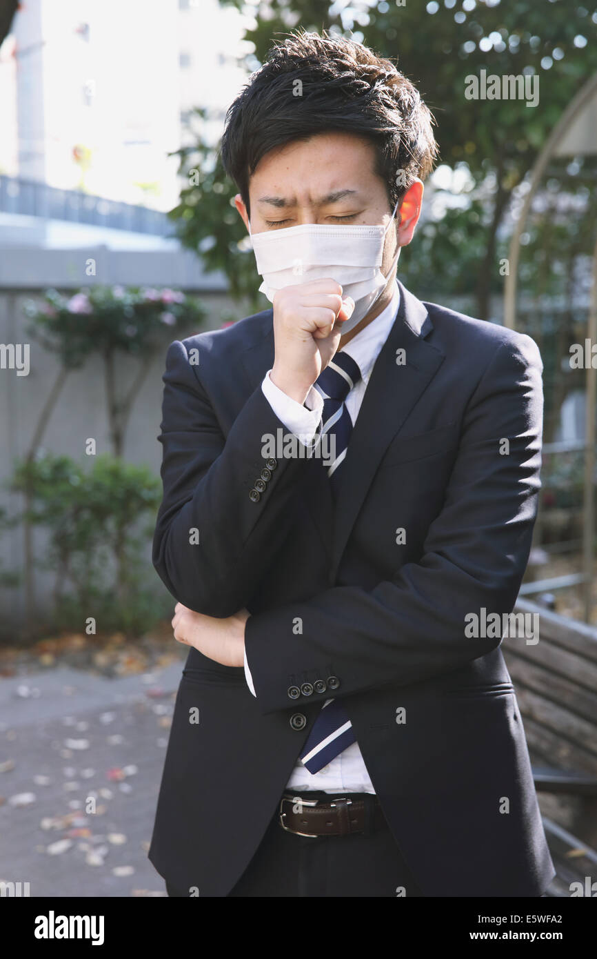 Sick Japanese young businessman in a suit at the park Stock Photo