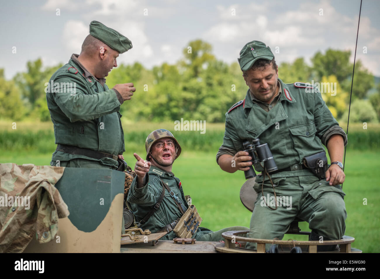 German soldier talking to comrades on a tank during reenactment of World War II fight Stock Photo