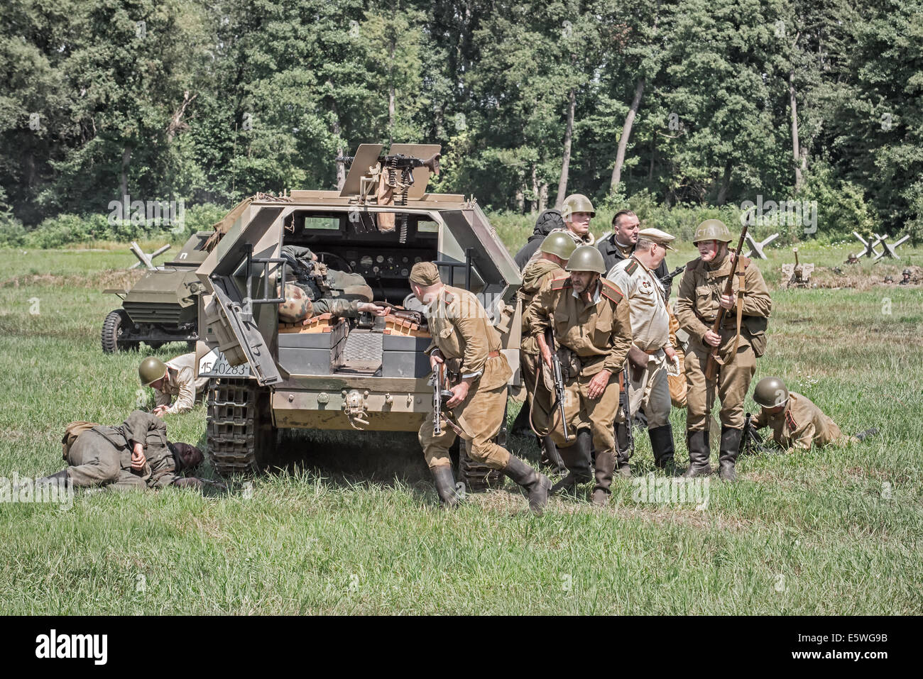 Squad of soviet soldiers capturing a german troop carrier during Reconstruction of a World War II fight. Stock Photo