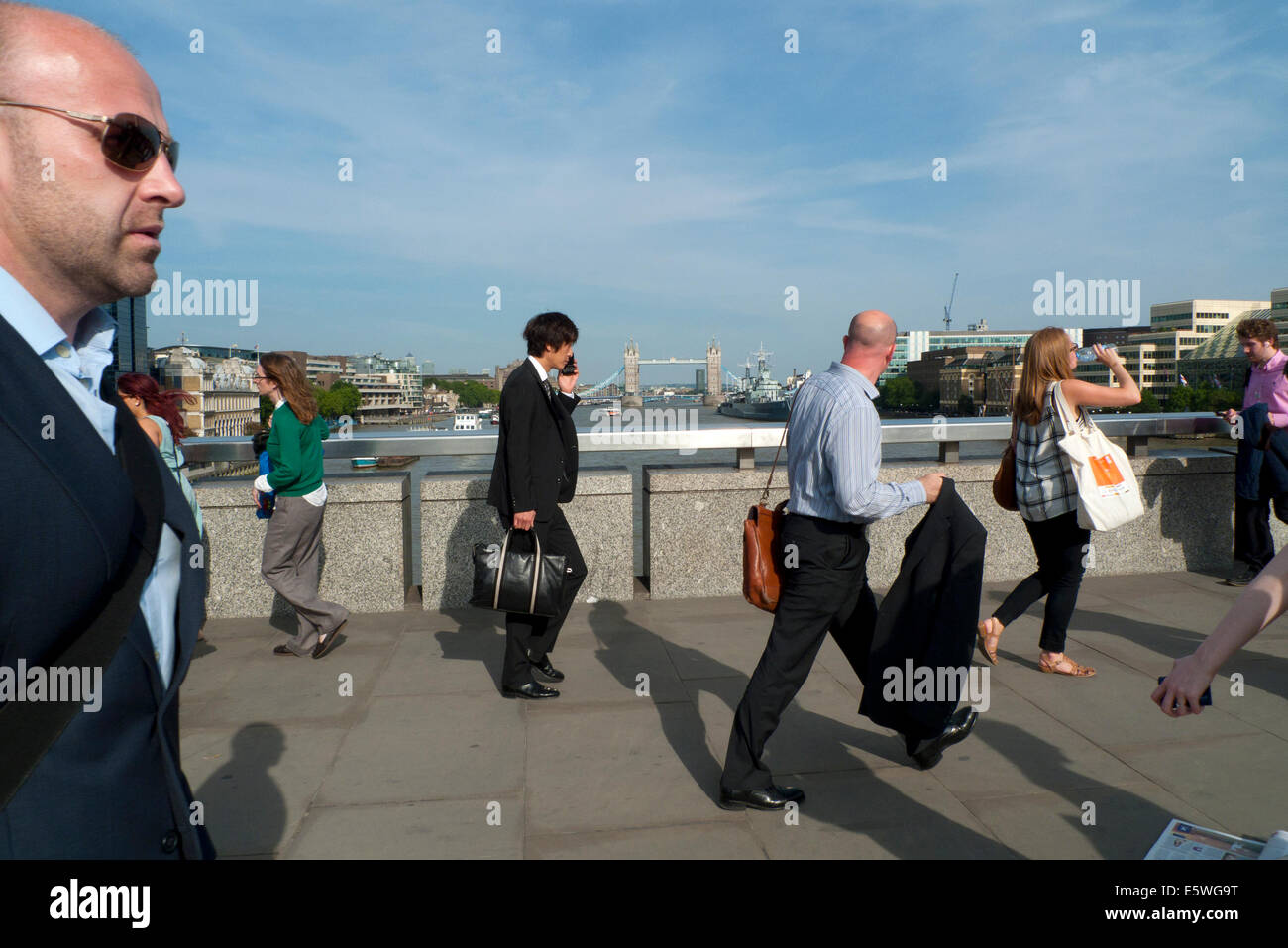 People crossing London Bridge after work in summer with a view of Tower Bridge and River Thames  London UK   KATHY DEWITT Stock Photo