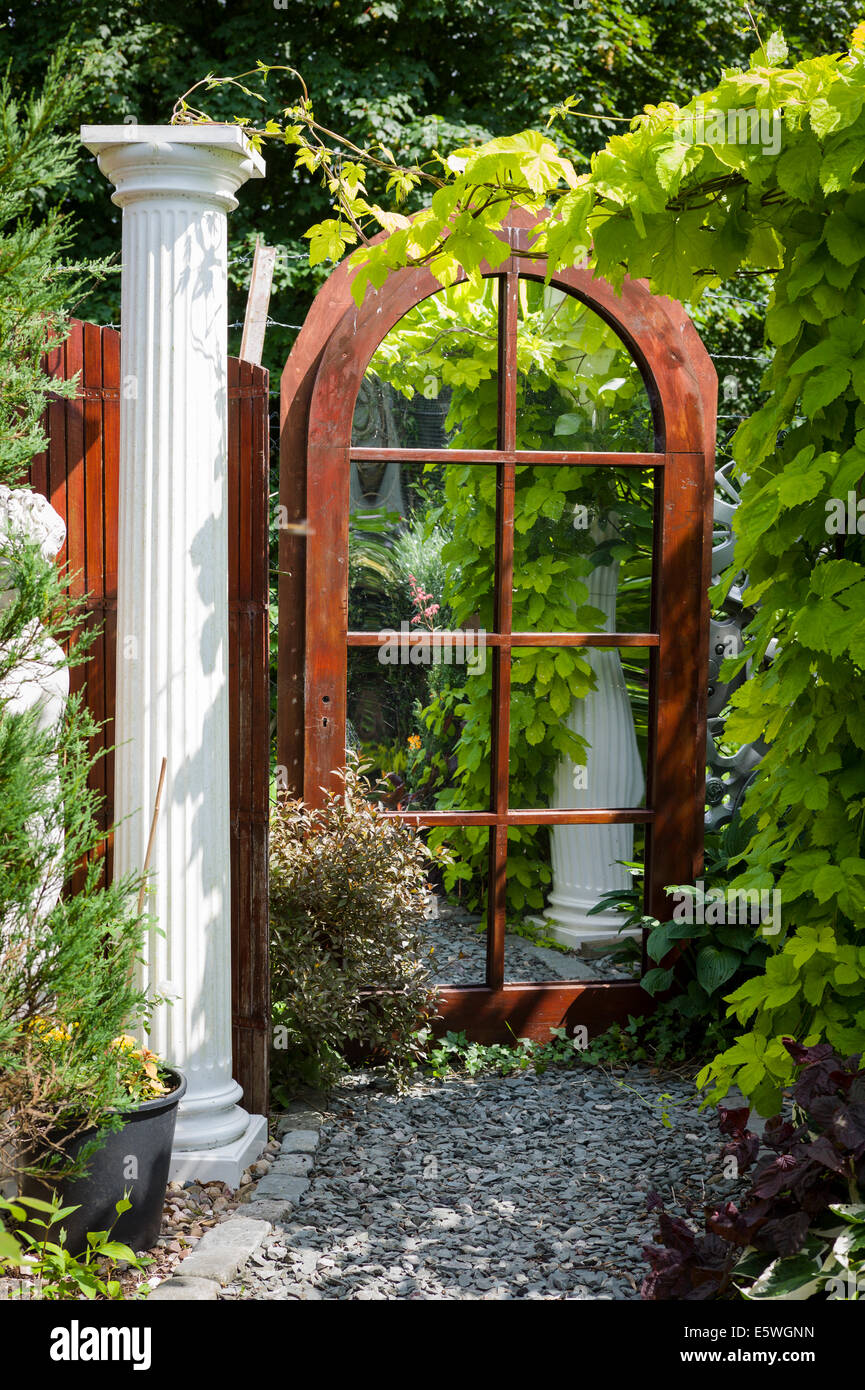 A mirror in a small courtyard garden creating the illusion of extra