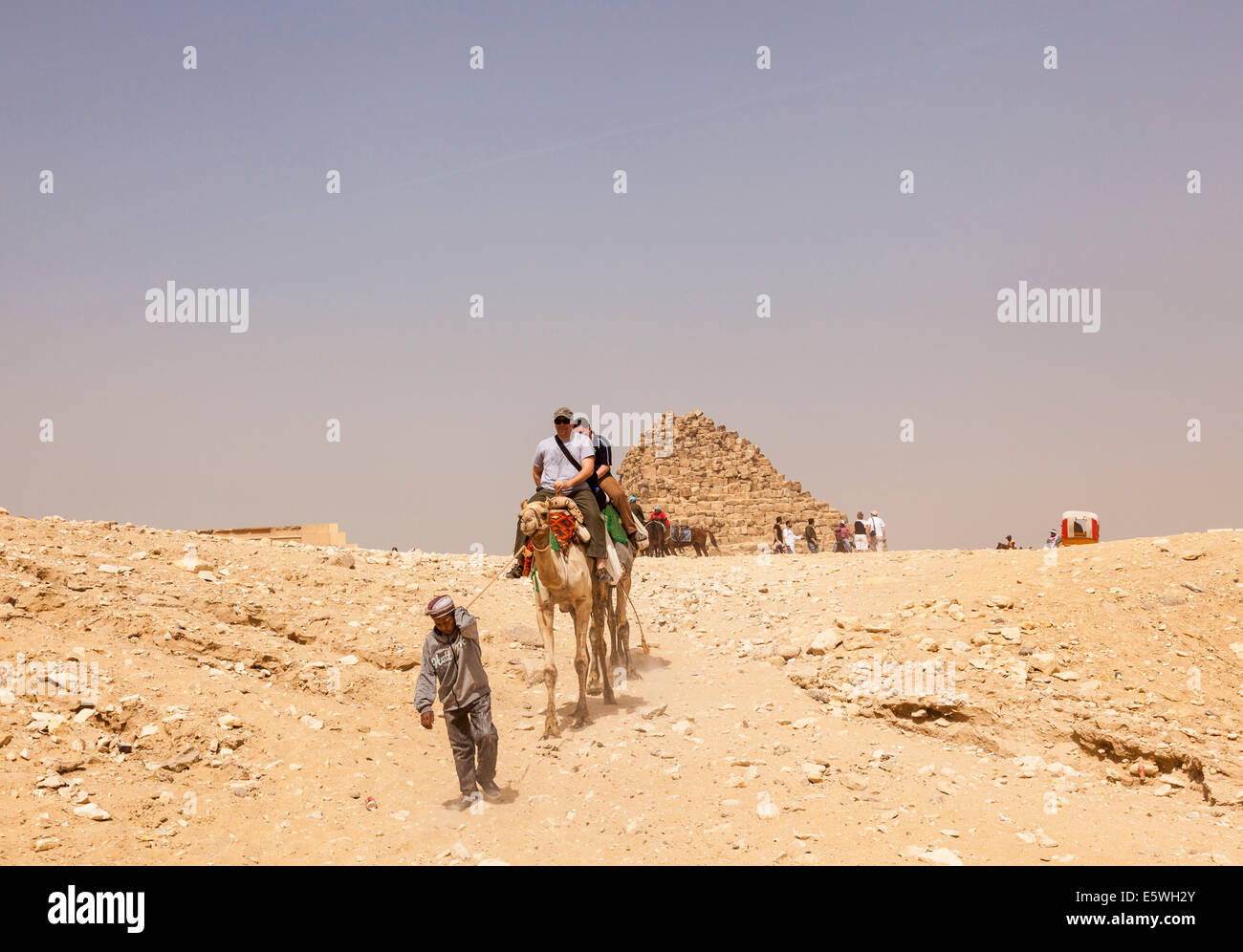 Pyramids, Egypt - Tourist riding a camel  by the Great Pyramid of Giza in Cairo, Egypt Stock Photo