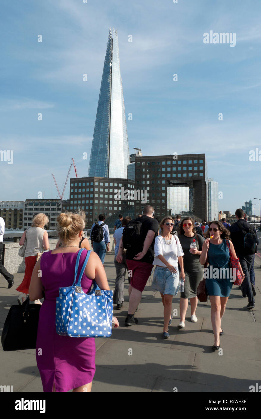 City of London office workers walking across London Bridge after work in summer after work and the Shard skyscraper London UK   KATHY DEWITT Stock Photo