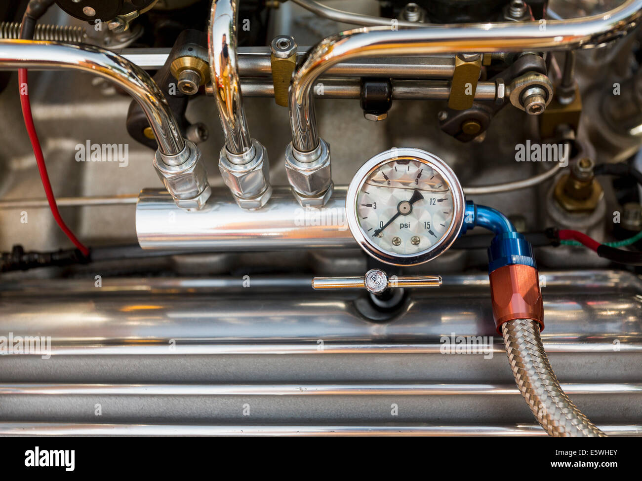 Engine compartment of antique hot rod car with focus on pressure gauge