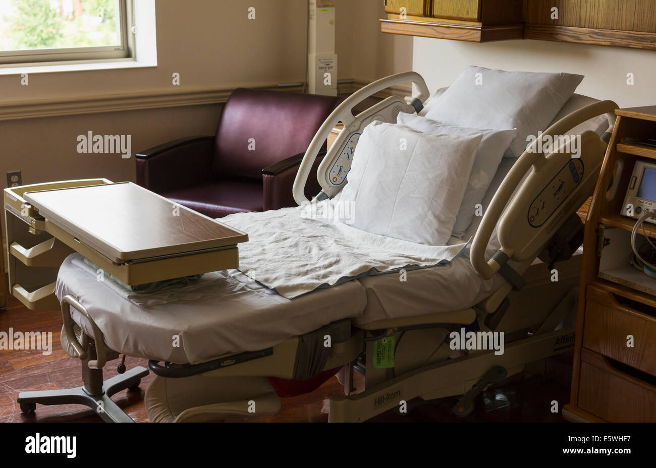 Empty hospital bed in USA maternity hospital with visitor chair Stock Photo