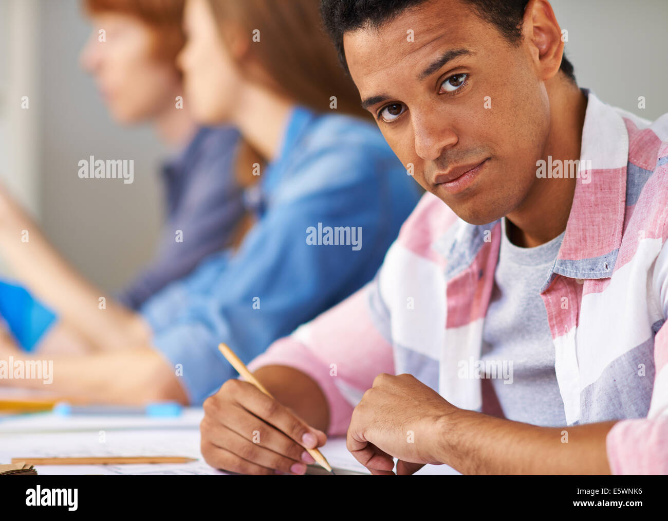 Smart guy looking at camera while sitting at lesson Stock Photo