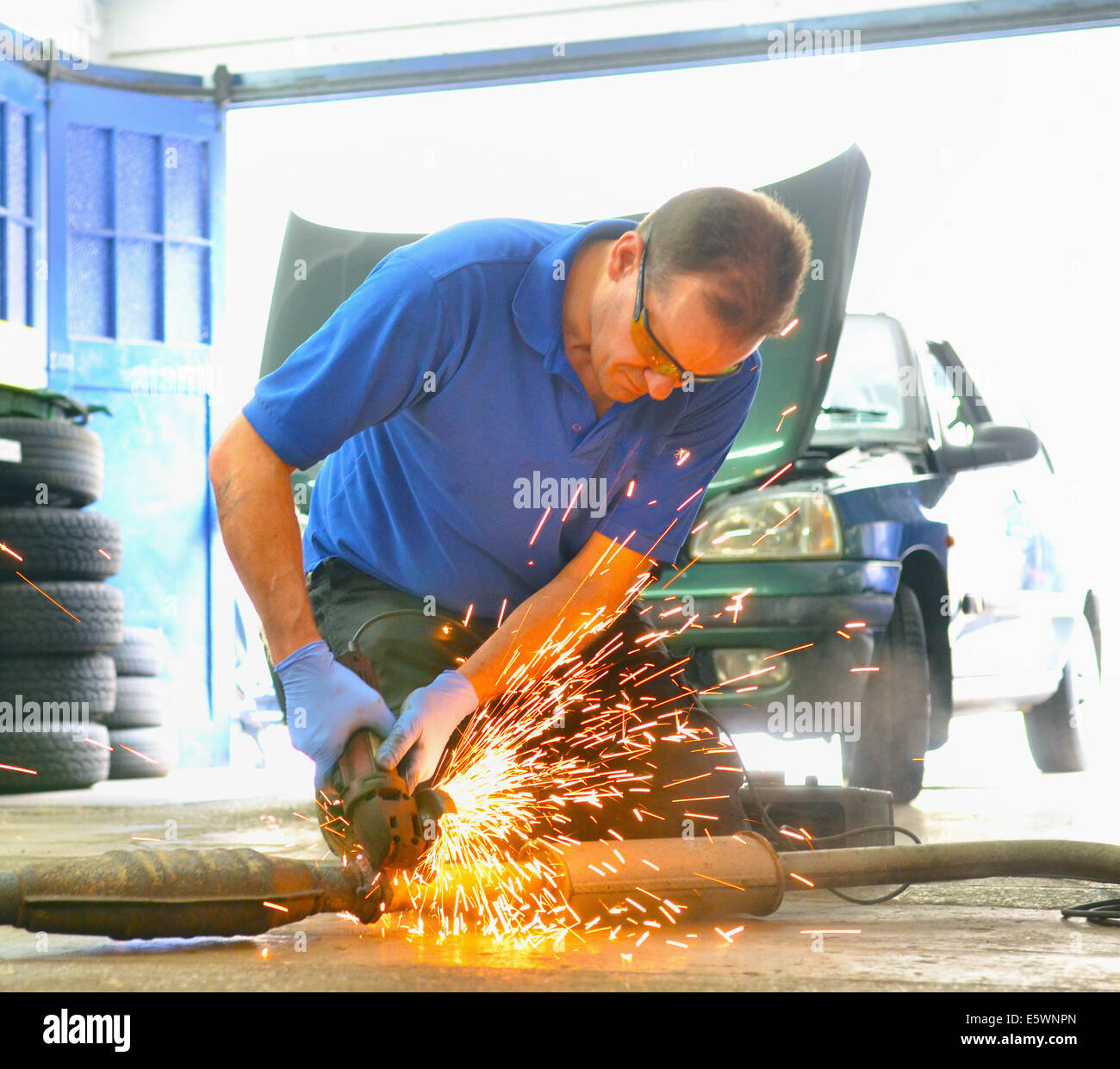 Mechanic cutting exhaust pipe with grinder Stock Photo