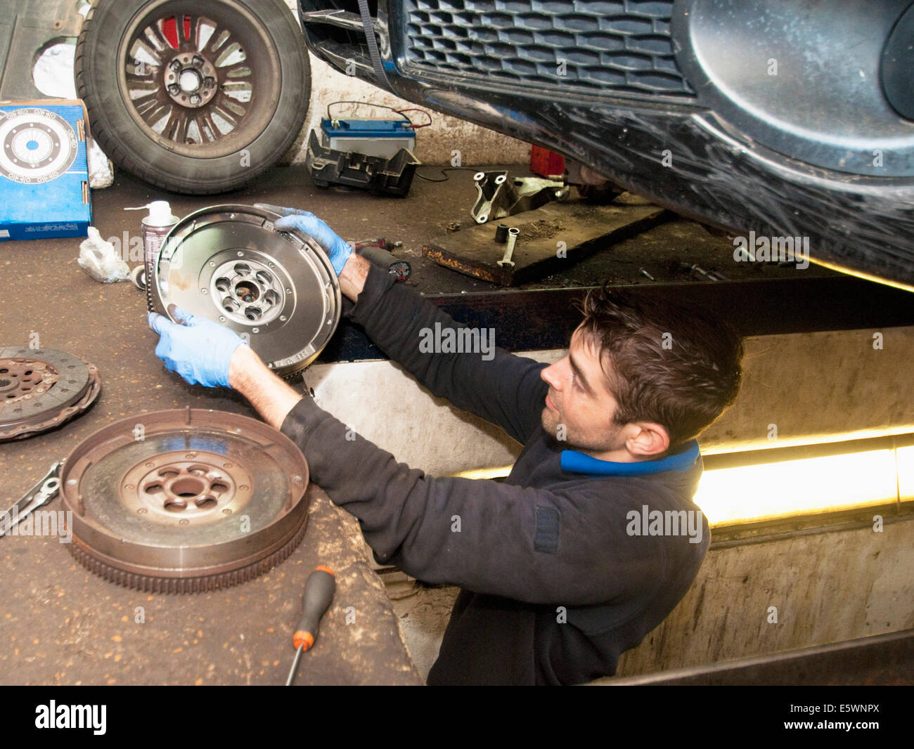 Mechanic checking disc of wheel underneath car Stock Photo